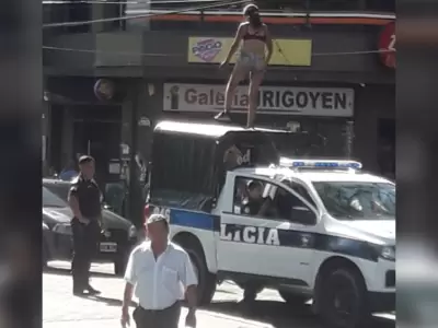 Mujer arriba del techo de un móvil policial