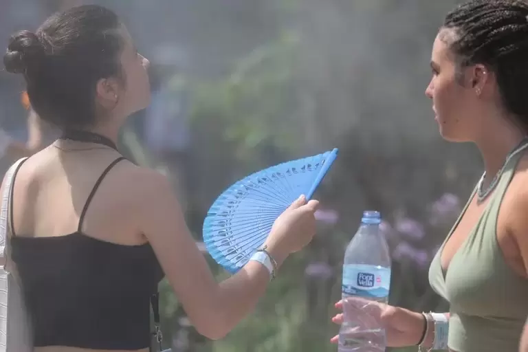 Jvenes se refrescan junto a una fuente de agua pulverizada en plena alerta amarilla en Valencia. (EFE/Ana Escobar)