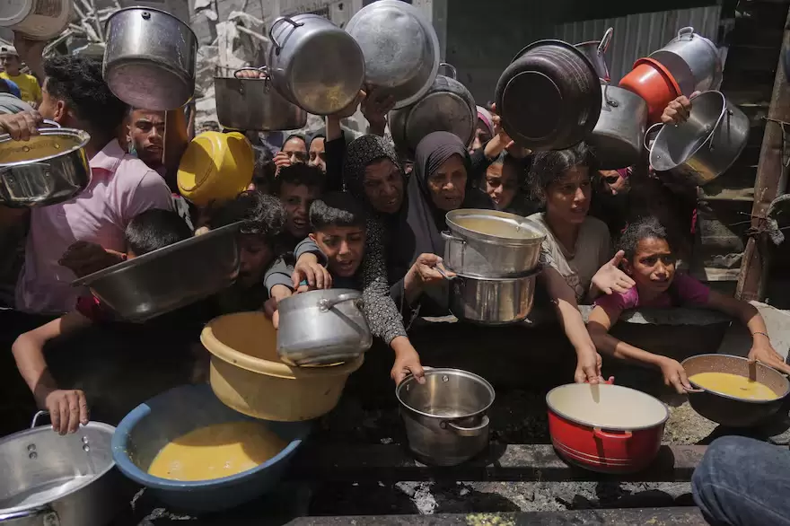 Palestinos luchan por conseguir alimentos donados en una cocina comunitaria en Jabalia, al norte de la Franja de Gaza, el lunes 19 de mayo de 2025