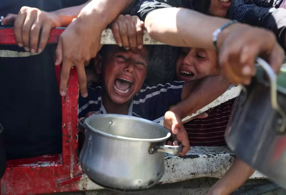 Palestinos esperan recibir comida de un comedor social, en medio de una crisis de hambre, en la ciudad de Gaza. REUTERS/Mahmoud Issa