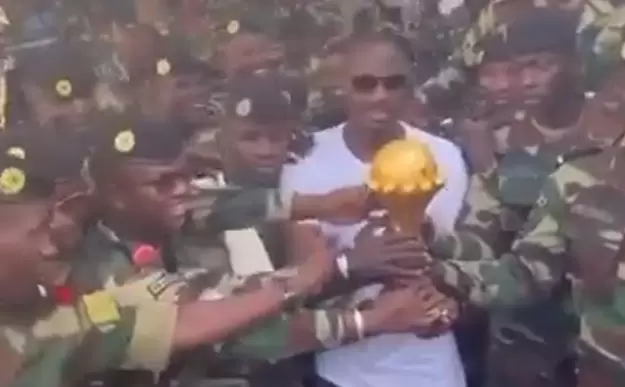El entrenador de Senegal llevando la Copa para que sea custodiada por el Ejército